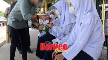 SERAH: Reduan (kiri) menyerahkan sumbangan zakat kepada murid-murid.