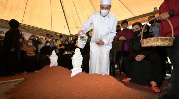 Wan Junaidi menyiram air mawar di pusara isterinya Allahyarhamah Feona di Tanah Perkuburan Islam Samariang, hari ini. - Gambar Bernama