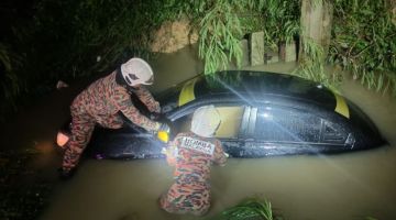 PERIKSA: Pasukan bomba menjalankan pemeriksaan terhadap kenderaan mangsa yang terbabas masuk ke dalam parit.