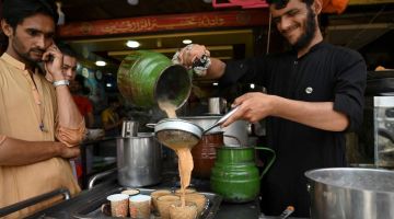 Seorang pekerja menuang teh ke dalam cawan untuk para pelanggan di sebuah restoran di Islamabad, kelmarin.