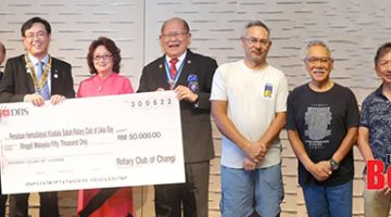 PRIHATIN: Lee (tengah) menerima replika cek RM50,000 daripada Eugene sambil disaksikan tetamu kehormat lain empat penunggang basikal dari Sabah.