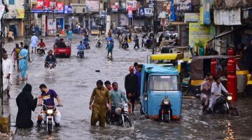 Orang ramai dilihat di jalan raya yang ditenggelami banjir selepas hujan monsun di Karachi pada Isnin lepas. — Gambar AFP