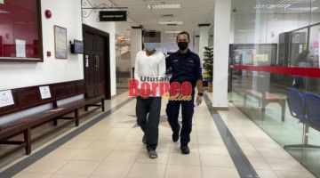 Tertuduh (kiri) yang didakwa melakukan jenayah seksual terhadap anak perempuannya diiring polis semasa berada di lobi Mahkamah Kuching.