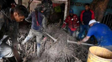 Penduduk membantu penyelamat menggali lumpur di dalam rumah yang musnah ketika mereka mencari mayat atau mangsa terselamat dalam kejadian tanah runtuh semasa hujan lebat di Las Tejerias, negeri Aragua pada Ahad lepas. — Gambar AFP