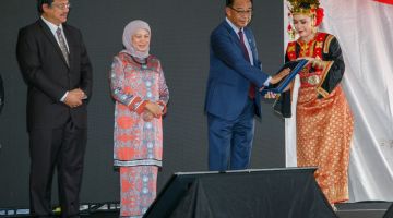 Abdul Karim ngengkahka tapa jari ba skrin tablet kelai bejadika Begunan Arkib Negara Malaysia Negeri Sarawak seraya diperatika (ari kiba) Dr Hazland enggau Nancy, kemari. -Gambar Muhammad Rais Sanusi