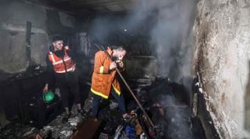 Anggota bomba Palestin memadamkan api di dalam sebuah rumah yang musnah dalam kebakaran di kem pelarian Jabalia di utara Kota Gaza kelmarin. — Gambar AFP