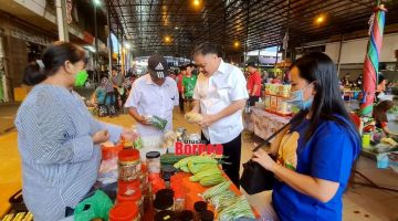 MESRA: Robert meluangkan masa membeli jualan peniaga di pasar tersebut sambil beramah mesra dengan pengunjung dan peniaga lain.