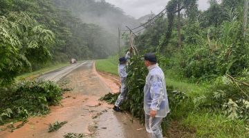 BERSIH: Sarjan Ambrose dan Koperal Nassier membantu membersihkan pokok tumbang di Jalan Marak Parak membabitkan laluan Kota Marudu- Ranau.