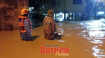 PANTAU: Anggota bomba dan APM memantau keadaan banjir di kawasan terjejas.