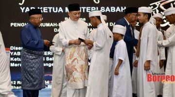 PRIHATIN: Hajiji (dua kiri) menyampaikan sumbangan duit raya kepada sebahagian pelajar Tahfiz pada majlis berkenaan.