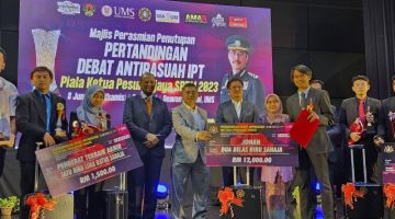 TAHNIAH: Azam menyampaikan hadiah kepada pemenang pertandingan debat di sini.