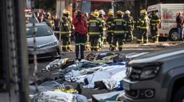 Mayat-mayat ditutupi kain dilihat di lokasi di mana sebuah bangunan lima tingkat terbakar di Johannesburg kelmarin. — Gambar AFP 