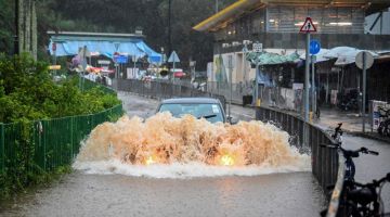 Sebuah kereta dilihat melalui jalan raya yang dilanda banjir selepas hujan lebat di Pulau Lantau di Hong Kong semalam. — Gambar AFP