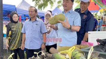 BANYAK PILIHAN: Ruslan (dua kanan) menunjukkan buah-buahan tempatan segar yang dijual di Tamu Kantor Padas Damit.