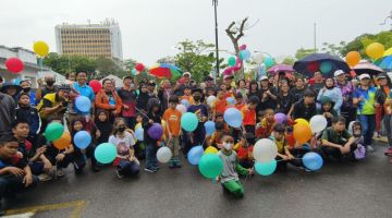 Yii (barisan belakang, tengah) merakamkan kenangan bersama pengunjung Hari Tanpa Kereta di Jalan Raja, Miri pada Sabtu. 