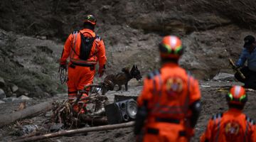 Anggota penyelamat bersama anjing pengesan memeriksa lokasi di mana sungai yang dicemari sampah-sarap melimpah selepas hujan lebat dan menghanyutkan beberapa rumah di kawasan melarat Dios es Fiel, di koloni Kjell Laugerud kelmarin. — Gambar AFP