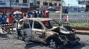 Orang ramai melihat bangkai kereta yang rentung di Monrovia kelmarin selepas pemandunya merempuh penyokong yang meraikan kemenangan Boakai dalam pilihan raya presiden baru-baru ini. — Gambar AFP