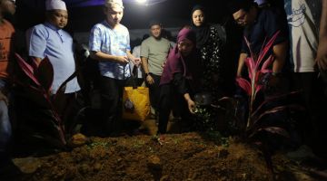 Balu Allahyarham Hamdan Ramli, 54, Norhamalini Ahmed, 53 menabur bunga di pusara Allahyarham suaminya di Tanah Perkuburan Islam Tambun dekat sini, kira-kira jam 11.50 malam tadi. -Gambar BERNAMA