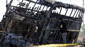 Ejen dari pejabat peguam bela tempatan memeriksa bas penumpang yang hangus selepas bertembung dengan trak di lebuh raya Mazatlan-Culiacan di daerah La Cruz, wilayah Sinaloa kelmarin. — Gambar AFP