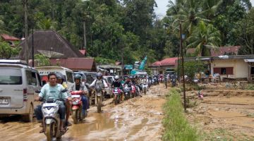 Pengguna jalan raya meredah laluan yang berlumpur susulan banjir kilat di Pesisir Selatan, Sumatera Barat kelmarin selepas hujan lebat melanda wilayah itu. - Gambar AFP