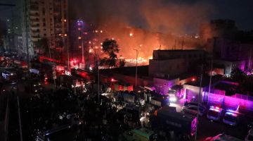 Orang ramai mengerumuni tempat kejadian ketika anggota bomba giat memadam kebakaran di Al-Ahram Studio dan bangunan sekitarnya di daerah Giza, kelmarin. - Gambar AFP
