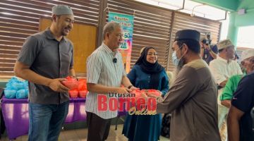 Fadillah (dua kiba) ngagihka bubur lambuk ngagai pengari penerima di Surau Al Hidayah Taman Sejoli, Kuching. Sama bisi dipeda Fazzrudin (kiba). - Gambar Roystein Emmor 