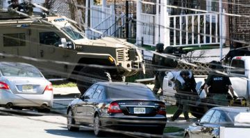 Anggota polis mengendong keluar seorang penghuni dari rumah yang dipecah masuk suspek di Trenton, kelmarin susulan siri serangan maut di Pennsylvania. - Gambar AFP