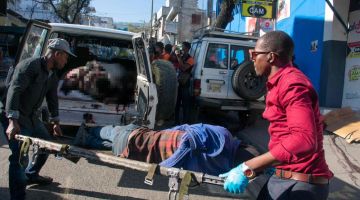 Paramedik mengangkat mayat seorang lelaki yang antara belasan orang yang dibunuh di jalanan oleh anggota kumpulan jenayah di Petion-Ville, Port-au-Prince kelmarin. — Gambar AFP