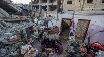 Keluarga Rabaya menikmati iftar yang serba sederhana berlatarkan kemusnahan di sekeliling mereka susulan serangan udara rejim Israel di Rafah, kelmarin. - Gambar AFP