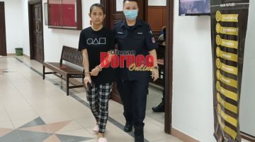 Jamilah (kiri) dibawa keluar dari kamar perbicaraan Mahkamah Sesyen Kuching, hari ini.