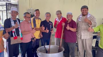 Dr Annuar (empat kiri) merakam gambar bersama penduduk Taman Desa Kemuyang, Sabtu lalu yang bergotong-royong memasak bubur lambuk sebelum diagihkan kepada orang ramai.