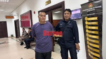 Kamri (kiri) diiringi polis keluar dari kamar Mahkamah Sesyen Kuching, hari ini selepas dijatuhkan hukuman.