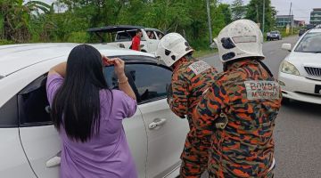  Anggota bomba berusaha membuka pintu kereta yang terkunci tersebut demi menyelamatkan dua kanak-kanak yang terperangkap di Miri, hari ini. 