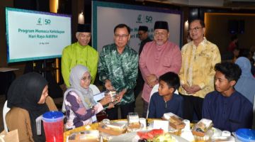 Dr Rundi menyampaikan sumbangan kepada anak-anak yatim pada majlis tersebut sambil disaksikan (dari kiri) Mohamed Syazwan, Iskandar dan Pang.