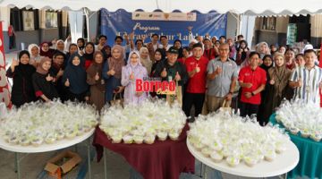 BUBUR LAMBUK: Tah Nia (tengah) merakamkan kenangan bersama pihak KTYS dan rakan komuniti selepas selesai memasak bubur lambuk sempena dengan program itu.