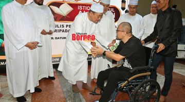 SUMBANGAN: Hajiji menyampaikan sumbangan daripada Perbadanan Baitumal Negeri Sabah kepada asnaf pada Majlis Istiqbal Nuzul Al-Quran Peringkat Negeri.