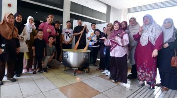 SEMANGAT: Rafiq Idris menggaul bubur lambuk pada Program Memasak dan Mengedar Bubur Lambuk anjuran UCSF.