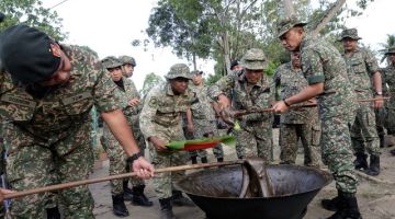 Malek (kanan) menggaul dodol ketika melawat anggota 26 RAMD bawah pemerintahan 5 Devisyen melakukan persiapan sambutan Aidilfitri di Markas Taktikal Keningau, baru-baru ini. - Gambar BERNAMA