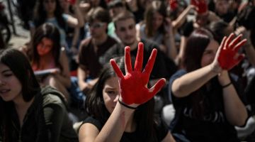 Penunjuk perasaan menunjukkan tangan berlumuran cat merah ketika berhimpun di Athens kelmarin untuk memprotes kurangnya tindakan dari pihak polis dalam menangani kes keganasan terhadap wanita di negara itu. — Gambar AFP