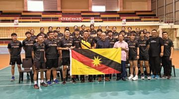 Lau (kanan) menyerahkan bendera kepada jurulatih pasukan lelaki, Pang Sii Chuong sambil diperhatikan yang lain di Sibu, hari ini.