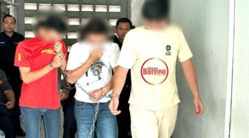 Anggota polis membawa dua daripada suspek (kanan dan tengah) keluar dari bilik mahkamah di Sibu semalam.