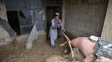Seorang warga Afghanistan membersihkan rumah beliau selepas dilanda hujan lebat dan banjir kilat , di Kandahar, kelmarin. — Gambar AFP