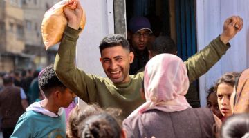 Seorang lelaki Palestin menunjukkan reaksi gembira selepas berjaya membeli roti bersubsidi di luar kedai roti di Kota Gaza pada Ahad lepas. — Gambar AFP