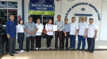 Abdul Samat (lima kanan) menunjukkan laporan polis bersama setiausaha politik lain di hadapan Balai Polis Satok hari ini.