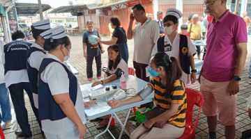 Orang ramai menjalani saringan kesihatan semasa program di Pusat Komersial Taman Rajang, hari ini.