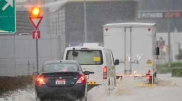 Kenderaan melalui jalan raya yang dilanda banjir semasa hujan lebat di Dubai kelmarin. — Gambar AFP 