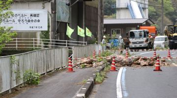 Pekerja semalam memeriksa bahagian lebuh raya yang ditutup selepas gempa bumi yang melanda bahagian selatan Jepun pada lewat malam sehari sebelumnya di bandar Ozu, wilayah Ehime. — Gambar AFP