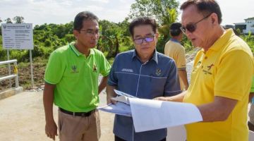 Lo (kanan) melihat pelan projek bersama Biro Pembangunan JKKK Kampung Tematu Stephen Jepeng (kiri) dan Ketua Kaum Kampung Tematu Geofrey Tahang (tengah) di atas jambatan konkrit yang baharu di Lorong 2 Kampung Tematu hari ini.