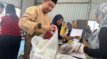 Lukanisman memasukkan bawang merah ke dalam plastik ketika meninjau kaunter jualan PJRB di  Dewan Kampung Muhibbah Ladang 3.