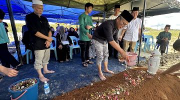 Dr Annuar menyiram air mawar ke atas pusara bapanya Allahyarham Rapaiee Tarip yang telah selamat dikebumikan di Tanah Perkuburan Islam Kemuyang hari ini.